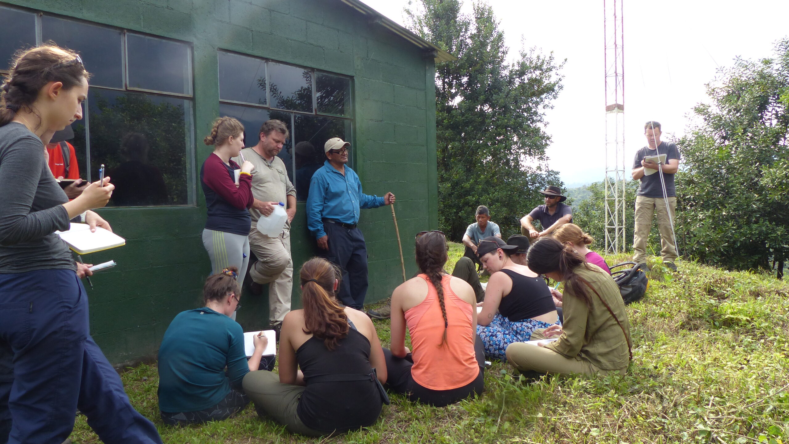 A group of students and volcanologist meet in front of an observatory at Volcán Santiaguito